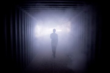 Silhouette of a man walking in a dark tunnel to the light