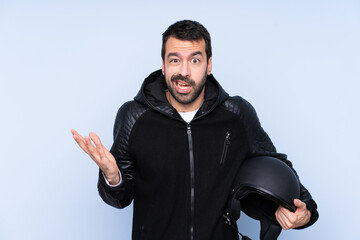Man with a motorcycle helmet over isolated background making doubts gesture
