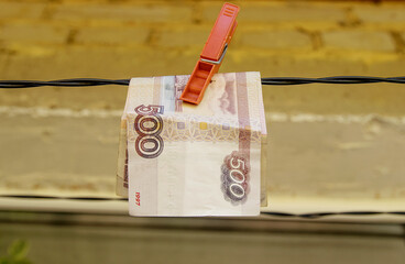 Russian paper banknote of five hundred rubles is attached with a clothespin to a clothesline for drying clothes