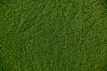 view of crumpled fabric texture with water drops. Dew drop on green background