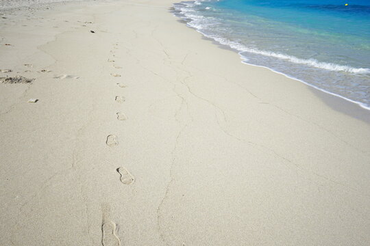 Footprints of human feet on the sand near the water on the beach. Furuzamami Beach in Zamami island, Okinawa, Japan. Image of summer vacation. - 日本 沖縄 座間味島 古座間味 ビーチ 足跡