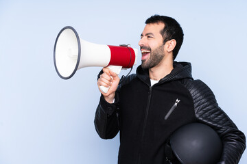 Man with a motorcycle helmet over isolated background shouting through a megaphone