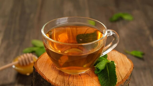 a mug of herbal tea on a wooden stump with mint and honey