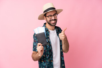 Young caucasian man over isolated background in vacation holding a passport and plane with thumb up
