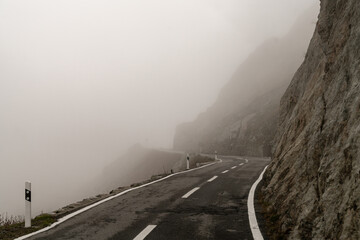 Gefährliche Bergstraße in den Bergen der Alpen im Nebel