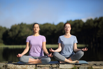 Fototapeta na wymiar Two women practicing yoga in the mountain