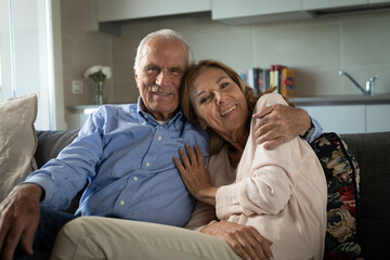 Obraz premium Cinematic shot of lovely happy mature couple enjoying time together is speaking and caressing each other with affection while sitting on sofa at home. Concept: love, family, marriage, happiness, age