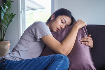 Obraz premium The girl hugged the pillow on the sofa inside the house sad and absent-minded feel bad about the things that happened.