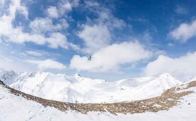 Winter mountains and helicopter against the blue sky of heliskiing