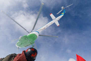 Helicopter takes off into blue sky with clouds