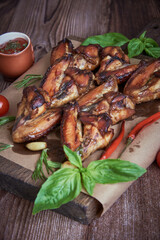 Delicious fried chicken wings lie on the serving board, decorated with various spices , herbs and vegetables.