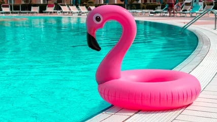 Tuinposter Hello summer. Pink inflatable flamingo in pool water for summer beach background. Trendy summer concept. © Maksym