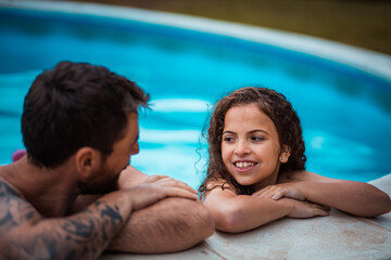 Father and daughter having talk in swimming pool.