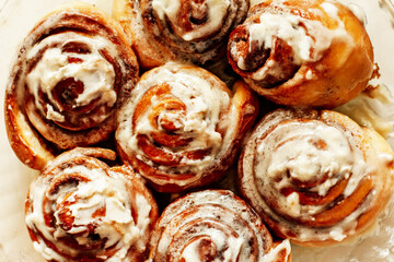 Close-up of fresh fragrant cinnabons with appetizing icing. Delicious homemade pastry or dessert at the bakery. Selective focus, top view