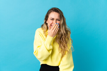 Young Brazilian woman isolated on blue background happy and smiling covering mouth with hand