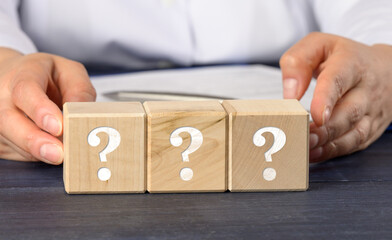 woman holding wooden cubes with question marks. Q&A concept, suspense