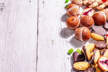 Assorted various cookies and cupcakes scattered on wooden boards background