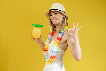 Young smiling woman in swimsuit showing pineapple isolated over yellow background.