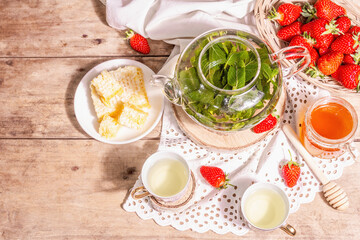 Teatime concept with aromatic mint tea, ripe strawberries, sweet honey