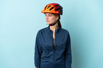 Young cyclist woman isolated on blue background looking to the side - obrazy, fototapety, plakaty