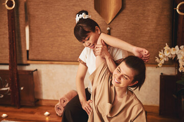 Female massage practitioner compressing side of joyful customer
