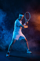 Fototapeta na wymiar Tennis player with racket in white t-shirt. Man athlete playing on dark background.