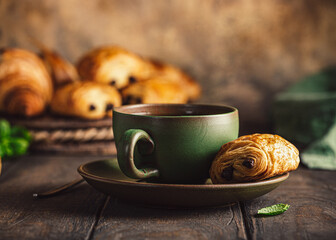 Green cup of tea with mini chocolate bun