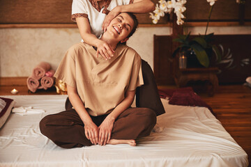 Pleased female relaxing under Thai yoga massage treatment