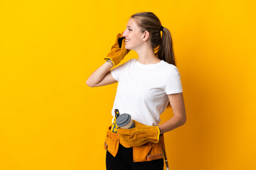 Young electrician woman isolated on yellow background holding coffee to take away and a mobile