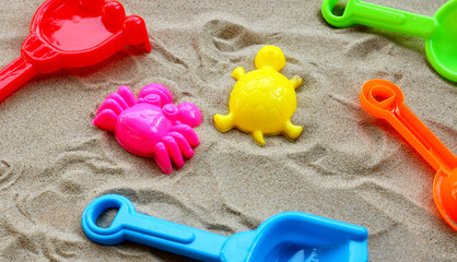 Fototapeta na wymiar Plastic toys, Colorful shovels on sand. Summer background concept