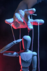 The human hand with marionette on the strings. Concept of control.