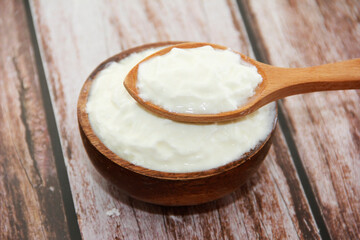 white milk yogurt in a wooden plate and spoon