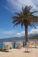 Złożone krzesła i stoły na tle palmy, morza i gór, Kreta, Grecja