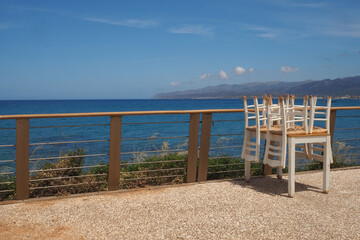 Złożone krzesła i stół na tle morza i nieba latem, Kreta, Grecja