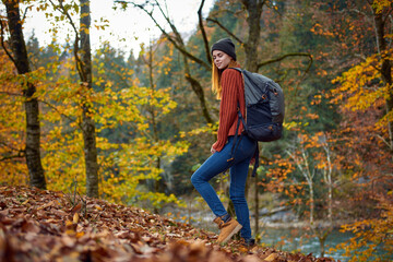 woman traveler with backpack walking in the park in autumn in nature side view