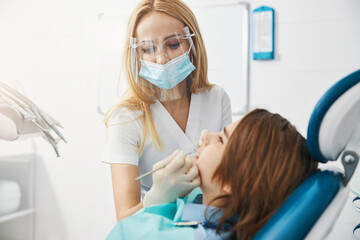 Dentist clinic employee examining teeth of minor patient
