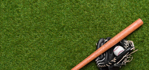 Baseball bat, glove and ball on green grass field. Sport theme background with copy space for text...