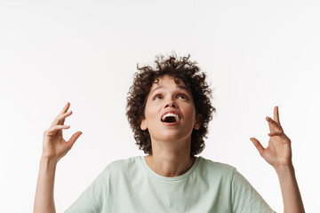Surprised curly brunette woman looking upward with her hands up