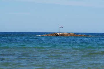 Flaga Grecji na małej kamienistej wyspie przy brzegu, Kreta