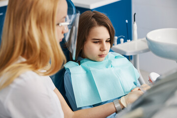 Concentrated boy looking at teeth mockup, showed by dentist