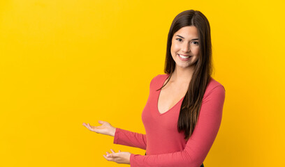 Teenager Brazilian girl over isolated yellow background extending hands to the side for inviting to come