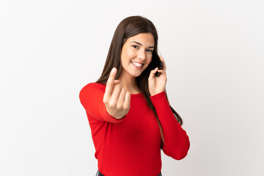 Teenager Brazilian girl using mobile phone over isolated white background doing coming gesture