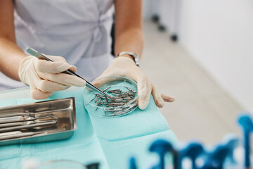 Dental expert grabbing handpiece nozzle with tweezers