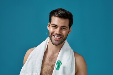 Portrait of nice looking brunette guy smiling at camera, holding dental floss in his mouth, posing...