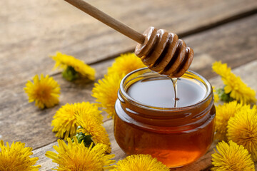 Dandelion syrup in a jar on a wooden background close-up.