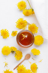 Jam dandelions in a jar on a white background, top view.