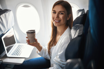 Female passenger with her favorite hot beverage during the flight