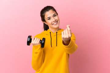 Young sport girl making weightlifting over isolated pink background making money gesture