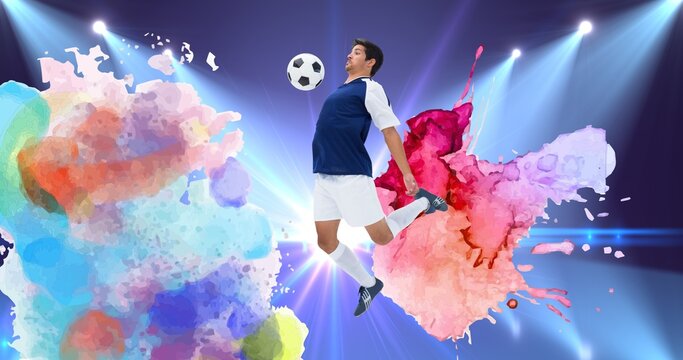Composition of football player with ball over colourful splodges and sports stadium background