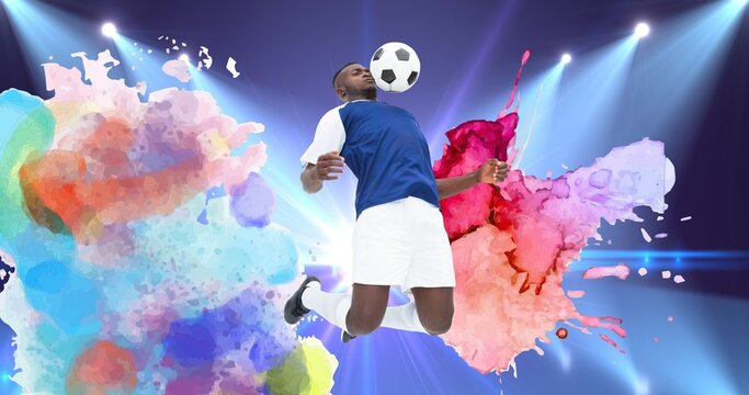 Composition of football player with ball over colourful splodges and sports stadium
